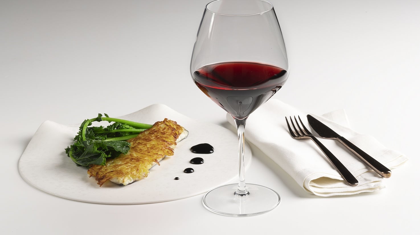 Filetto di branzino in crosta di patate, riduzione di vino rosso e cime di rapa