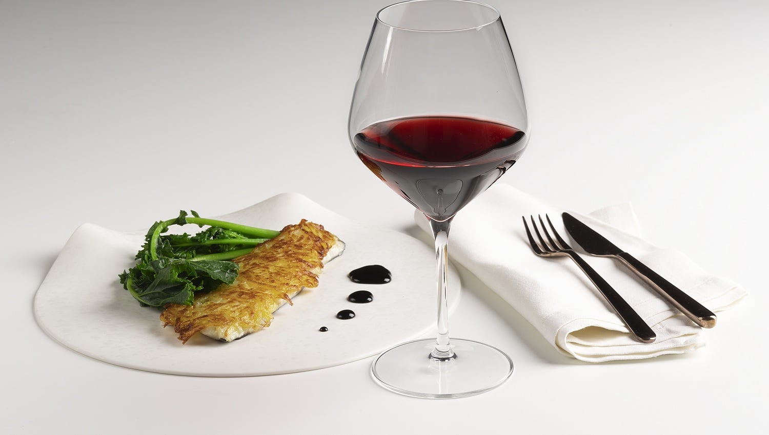 Filetto di branzino in crosta di patate, riduzione di vino rosso e cime di rapa