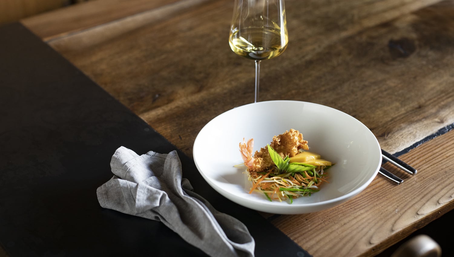 Insalata di verdure asiatica con mango e due varietà di gamberetti, servita con un bicchiere di vino bianco altoatesino ©IDM/Vini Alto Adige/Marion Lafogler
