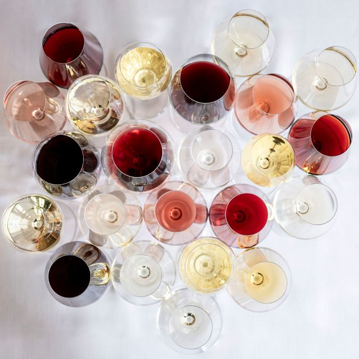 Molti calici da vino disposti uno accanto all’altro, fotografati dall’alto. Si distinguono diversi vini: bianchi, rossi, spumanti e rosé, ognuno servito in un bicchiere diverso.