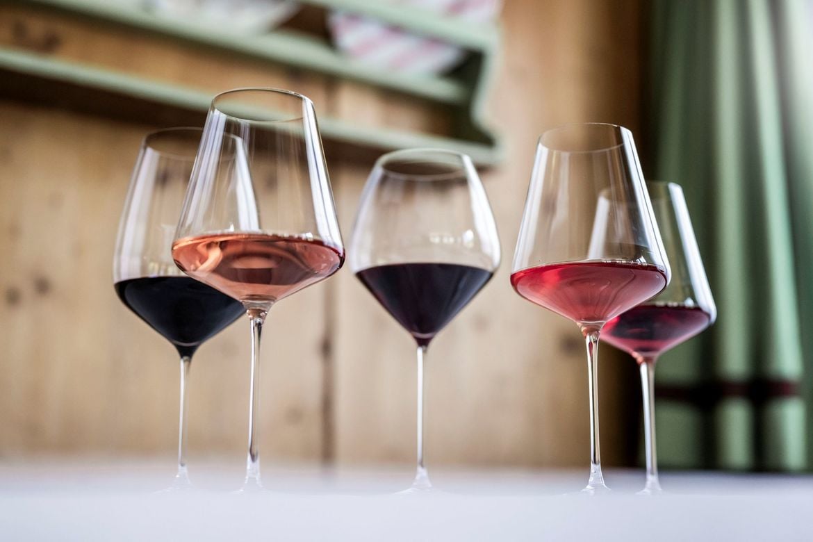 Una serie di calici ampi con apertura larga, contenenti vini rossi, tra cui due con apertura più stretta.