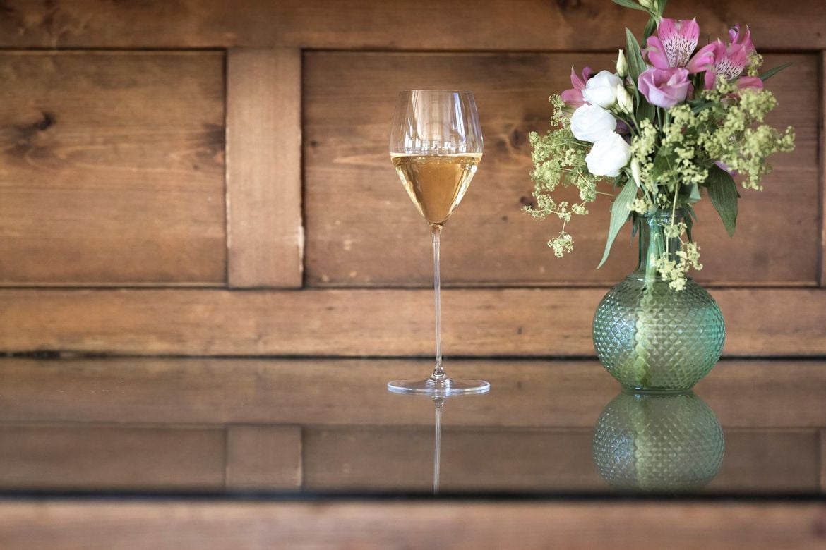 Un calice da spumante pieno, accanto a un mazzo di fiori.