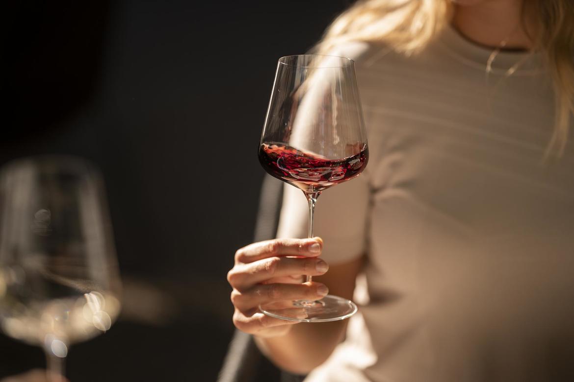 Una donna fa roteare un bicchiere di vino rosso.